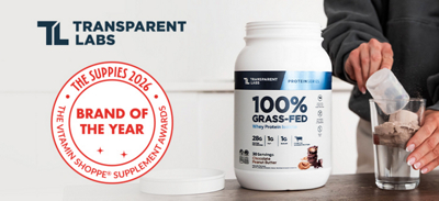 Woman pouring down a glass one scoop of protein powder from a transparent labs protein container next to a milk frother