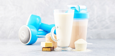 Protein Powder Powder-Ups.  Crush your goals from muscle building and recovery to energy, weight control, and more is written in dark blue font.  Image is also showing 3 scoops with protein powder, dumbbells, protein shakes and protein bars